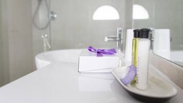 Un baño con lavamanos blanco, un espejo y artículos de tocador en la encimera.