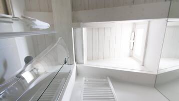 Et moderne, minimalistisk badeværelse med en glasbrusekabine, et indbygget toilet og et vindue, der giver naturligt lys.