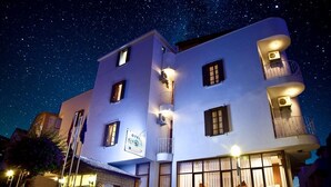Un hôtel à plusieurs étages, doté d’une façade blanche, de balcons et d’une enseigne indiquant qu’il s’agit d’un « OTEL ».