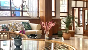 Un salon bien éclairé, avec un canapé, une table basse et une plante en pot.