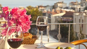 Une table dressée avec de la nourriture et du vin, offrant une vue panoramique sur des montagnes et un plan d’eau.