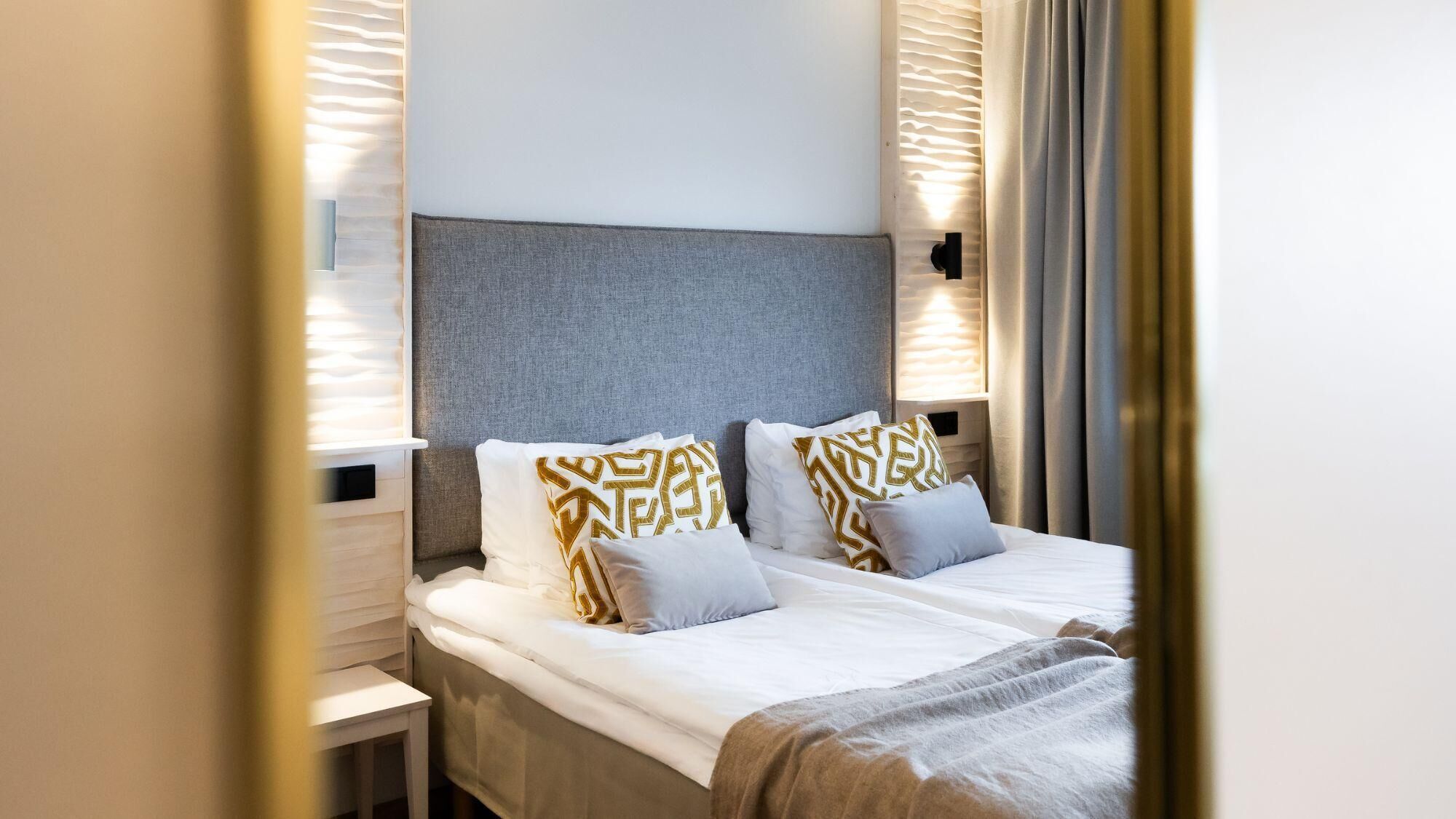 A hotel room with a bed, a bedside table, and a headboard.
