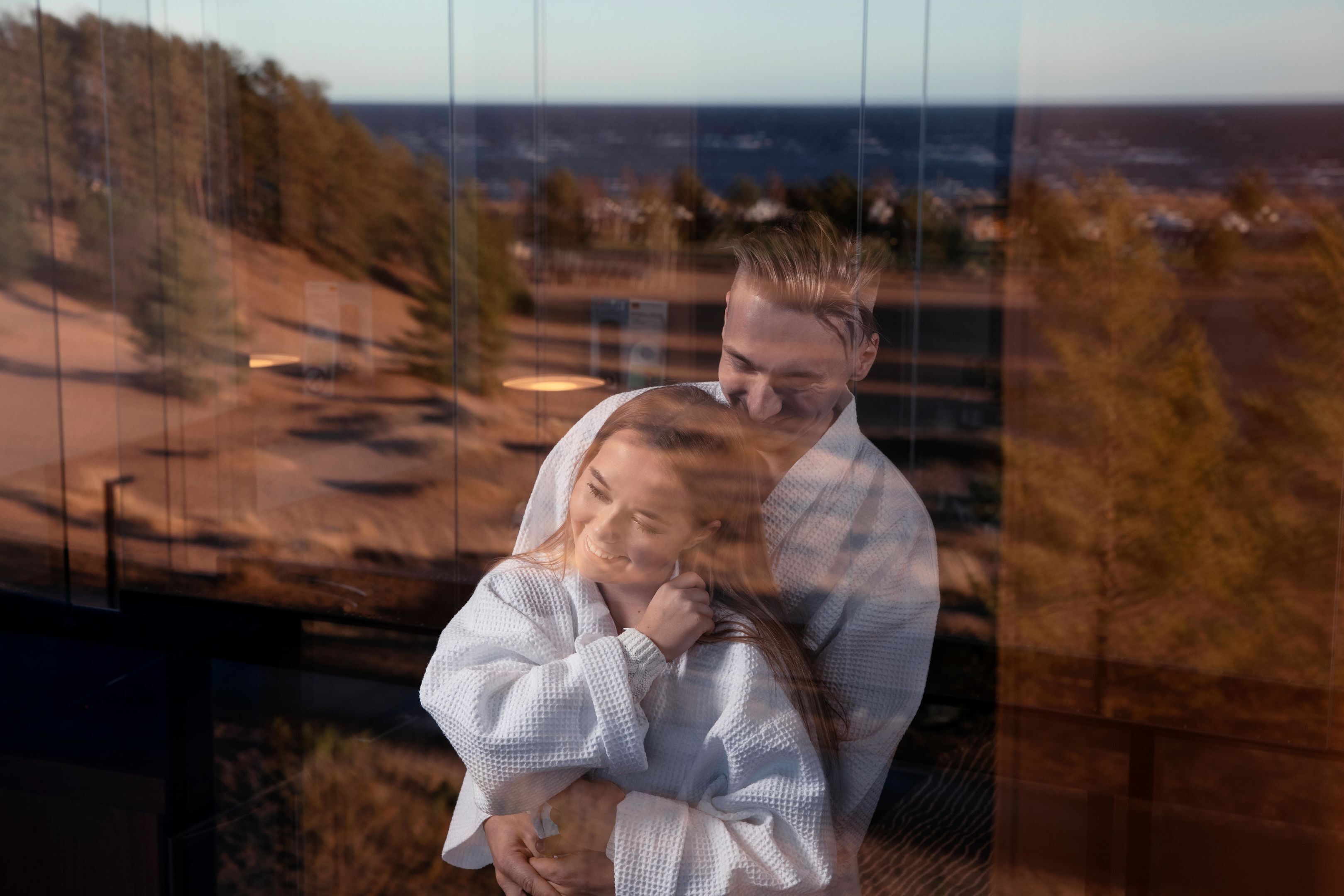 Ein Paar, das sich umarmt, mit Blick auf eine Landschaft durch ein Fenster.