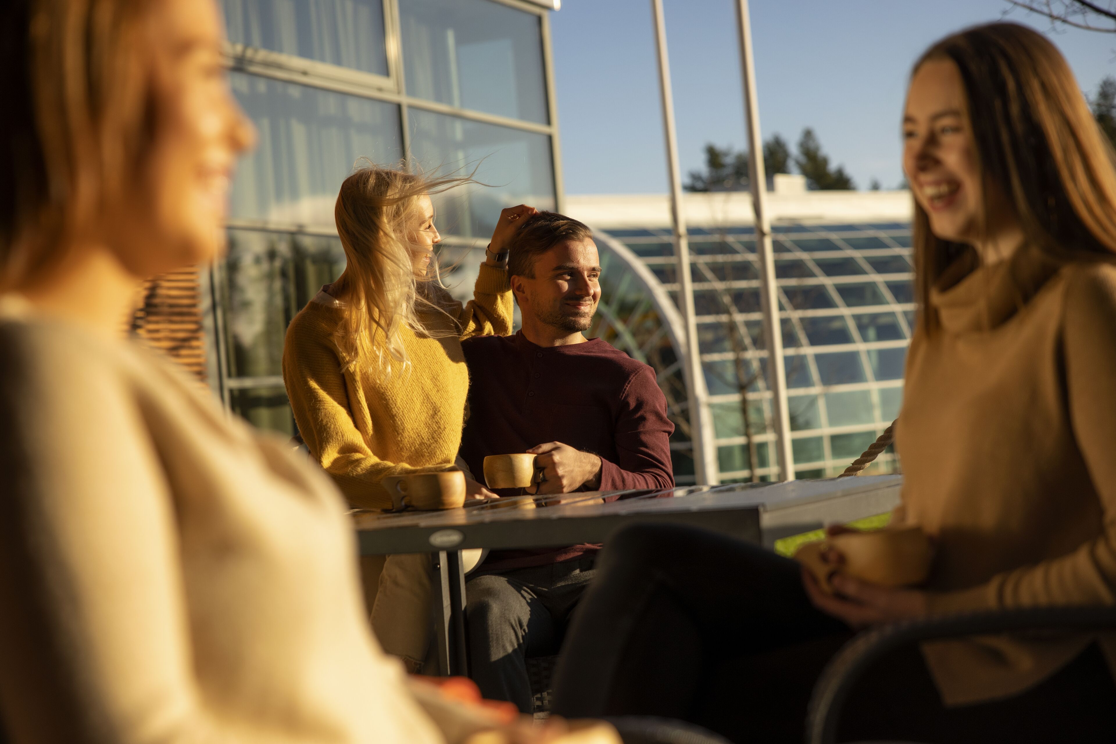 Un grupo de personas sentadas alrededor de una mesa en un edificio moderno con ventanales amplios.
