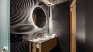 Un baño moderno con un tocador de madera, un espejo grande y una pared con textura.