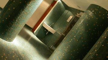 Ein Badezimmer mit einer gewölbten Bodenform, einem Waschbecken und einem Spiegel.