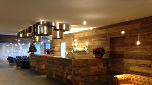 En modern entréhall med en receptionsdisk i trä, lädersitsar och en väggbeklädnad av sten.