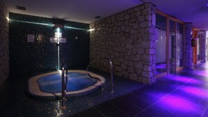 Ett spaområde med ett bubbelbad, en stenmur och ett kaklat golv.