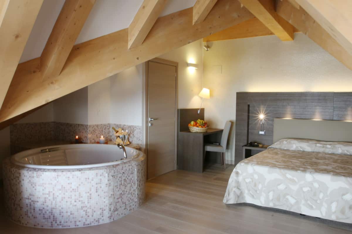 Un dormitorio con una cama grande, un baño con bañera y una mesita con frutero.