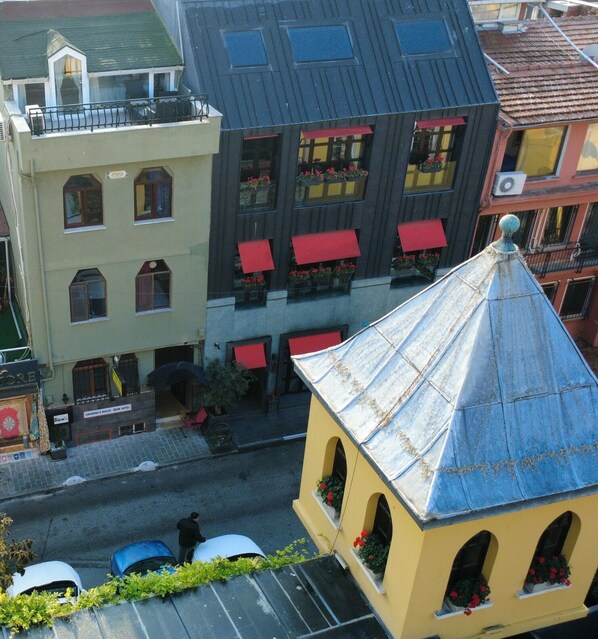 A street view with buildings, including a hotel with red awnings and a yellow building with a blue roof.