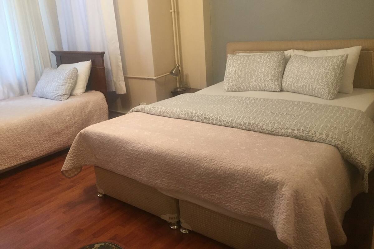 Ein Hotelzimmer mit zwei Betten, einem Nachttisch, einer Lampe und einem Fenster mit Vorhängen.