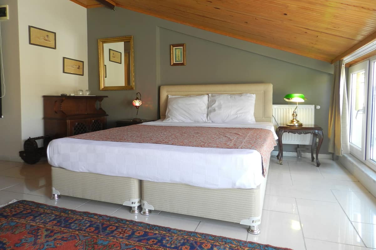 A bedroom with a large bed, a bedside table with a lamp, a dresser, and framed pictures on the wall.