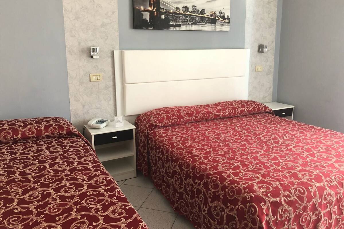 A hotel room with two beds, a nightstand with a phone, a wall-mounted picture, and a bedside table.