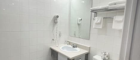 Une salle de bain moderne avec des carreaux blancs, un lavabo, un miroir avec éclairage intégré, un porte-serviettes et des toilettes.