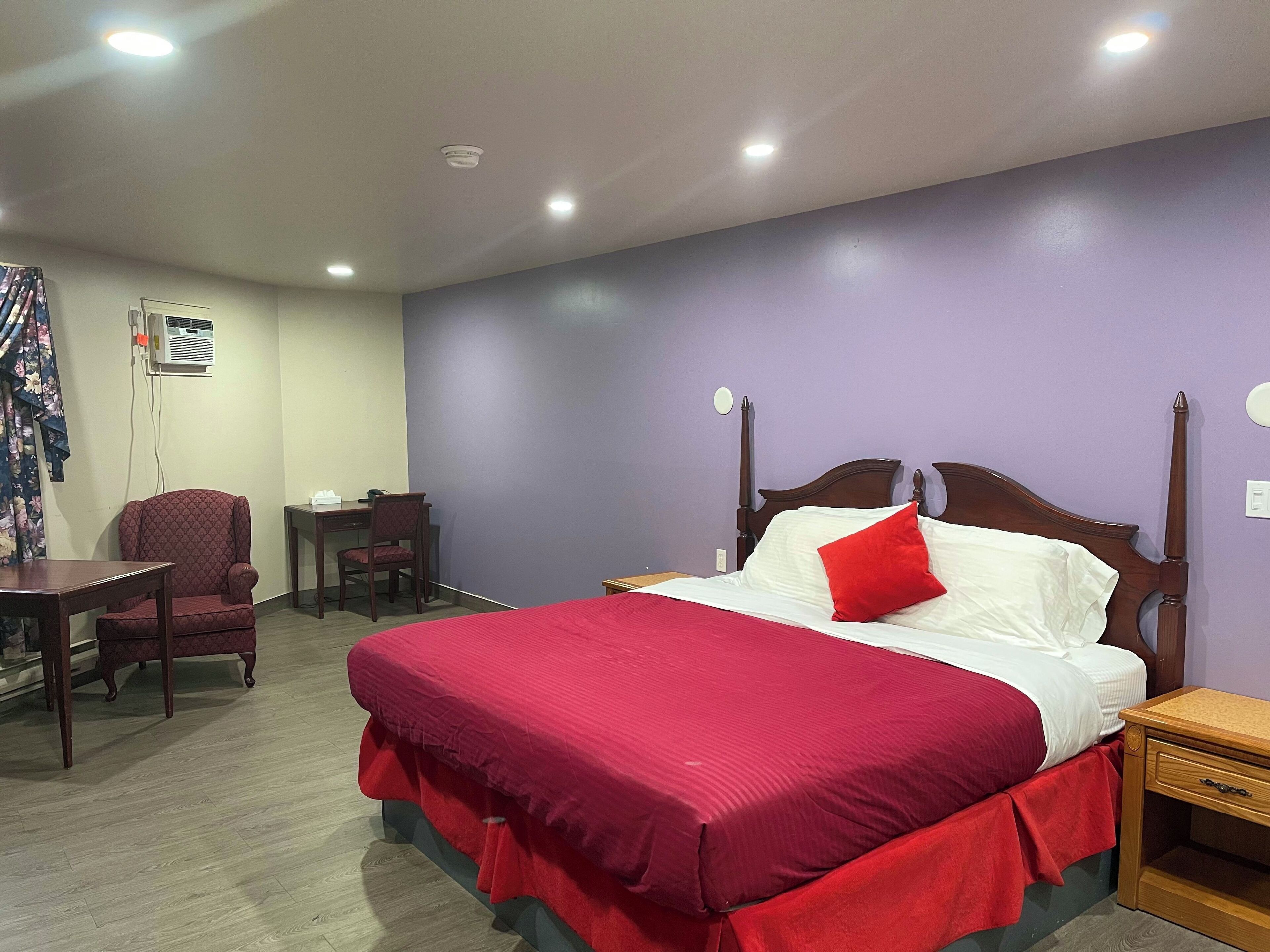Une chambre d’hôtel avec un grand lit, un bureau, une chaise et une petite table.