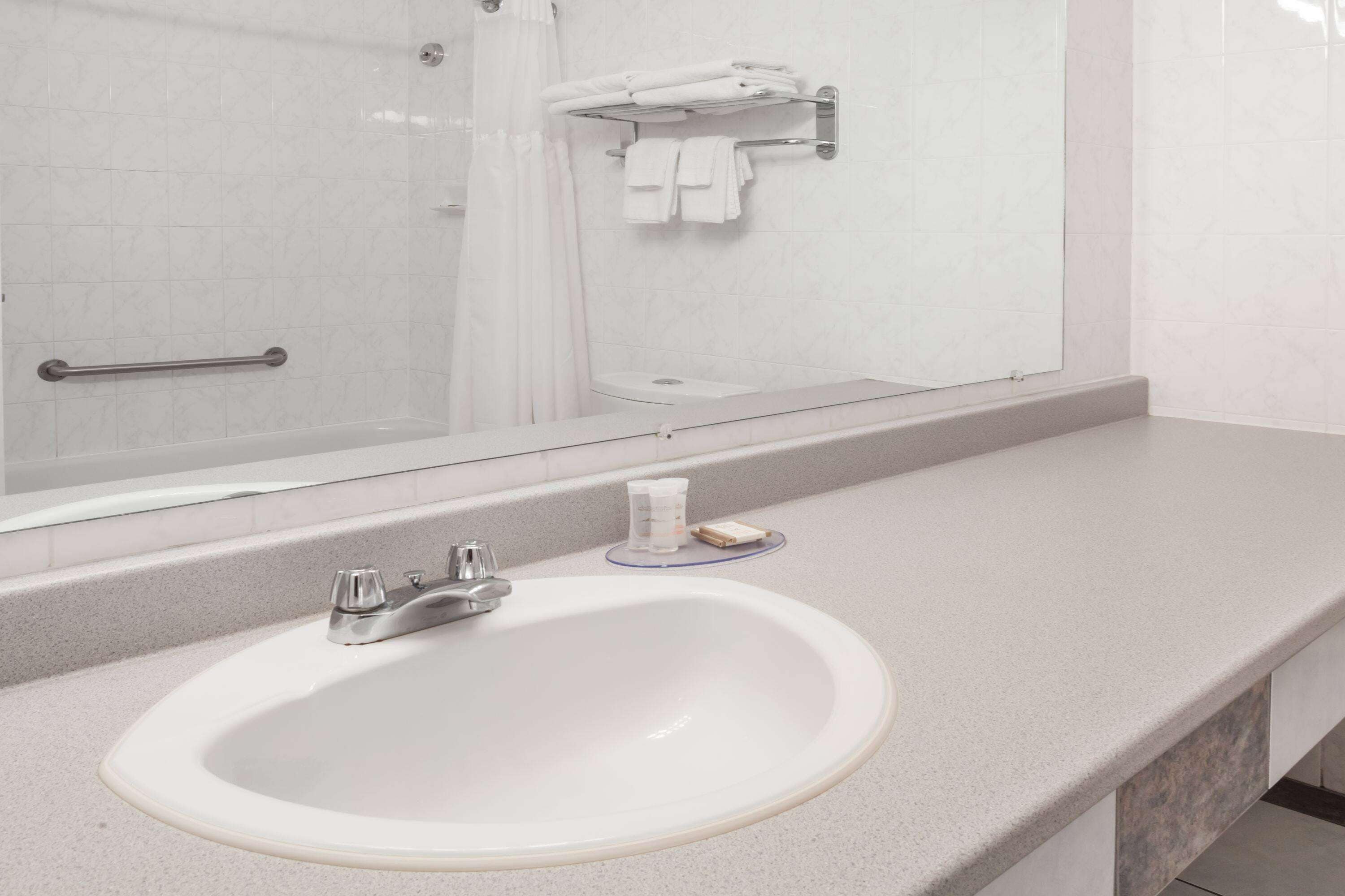 A bathroom with a white sink, a mirror, and a towel rack.