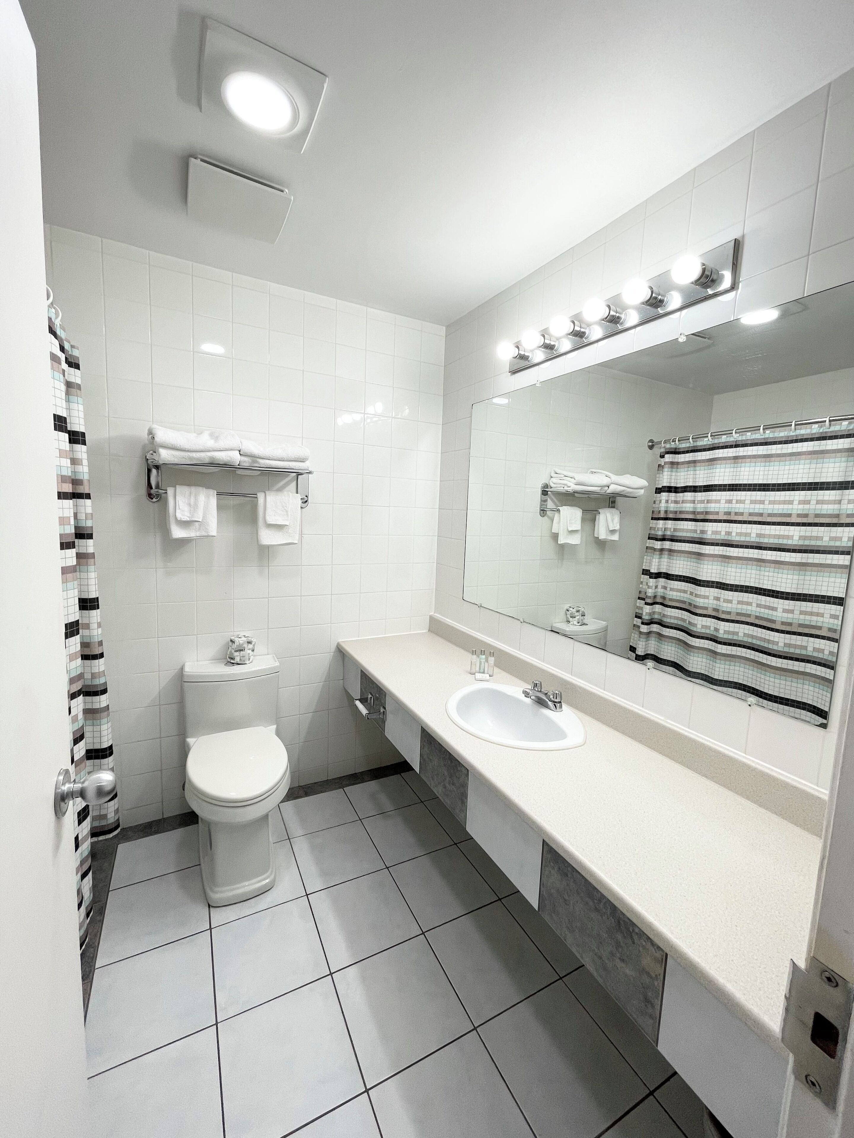 Un baño moderno con inodoro, lavamanos y espejo.