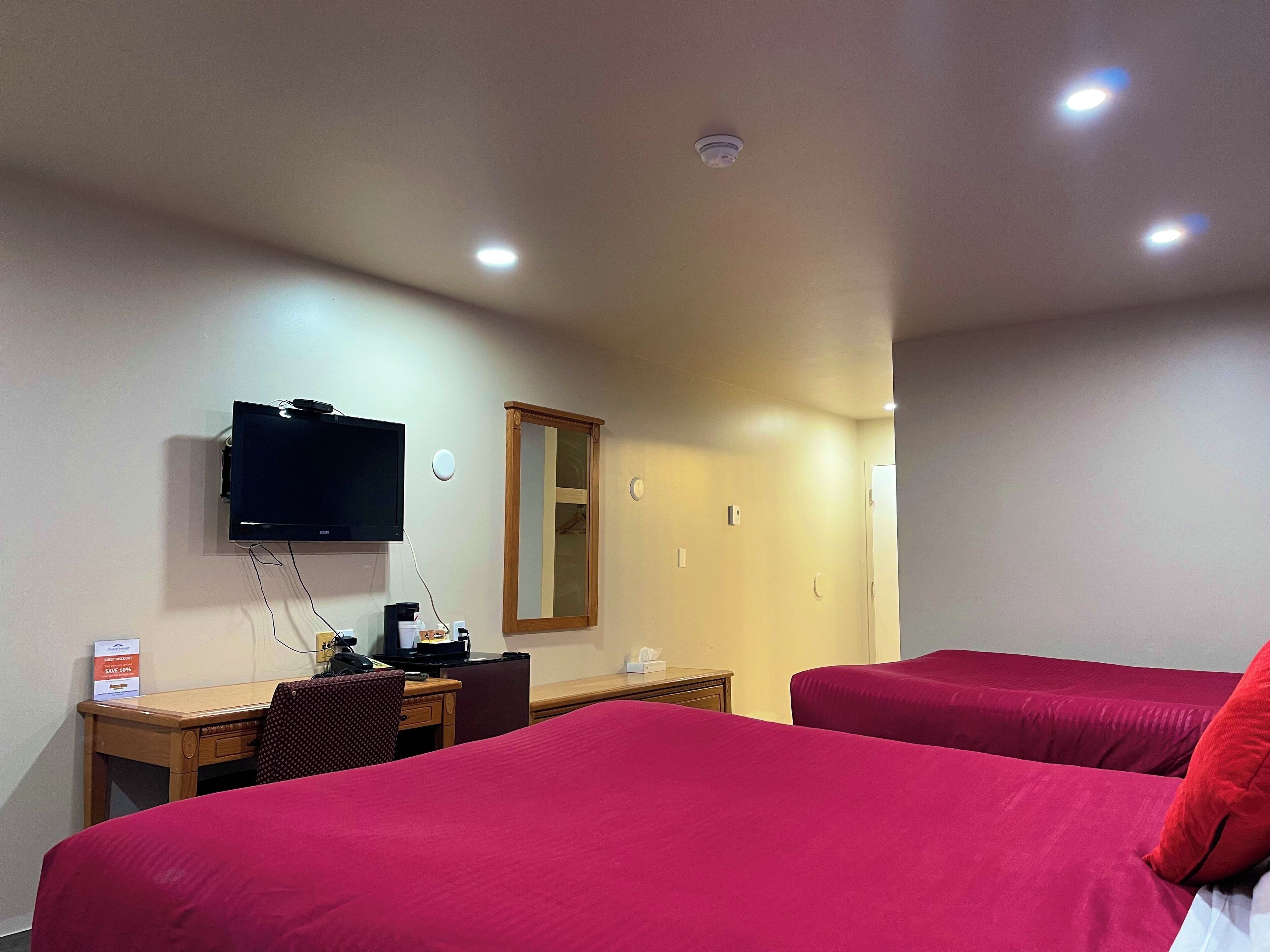 Een hotelkamer met twee bedden, een bureau, een televisie en een spiegel.
