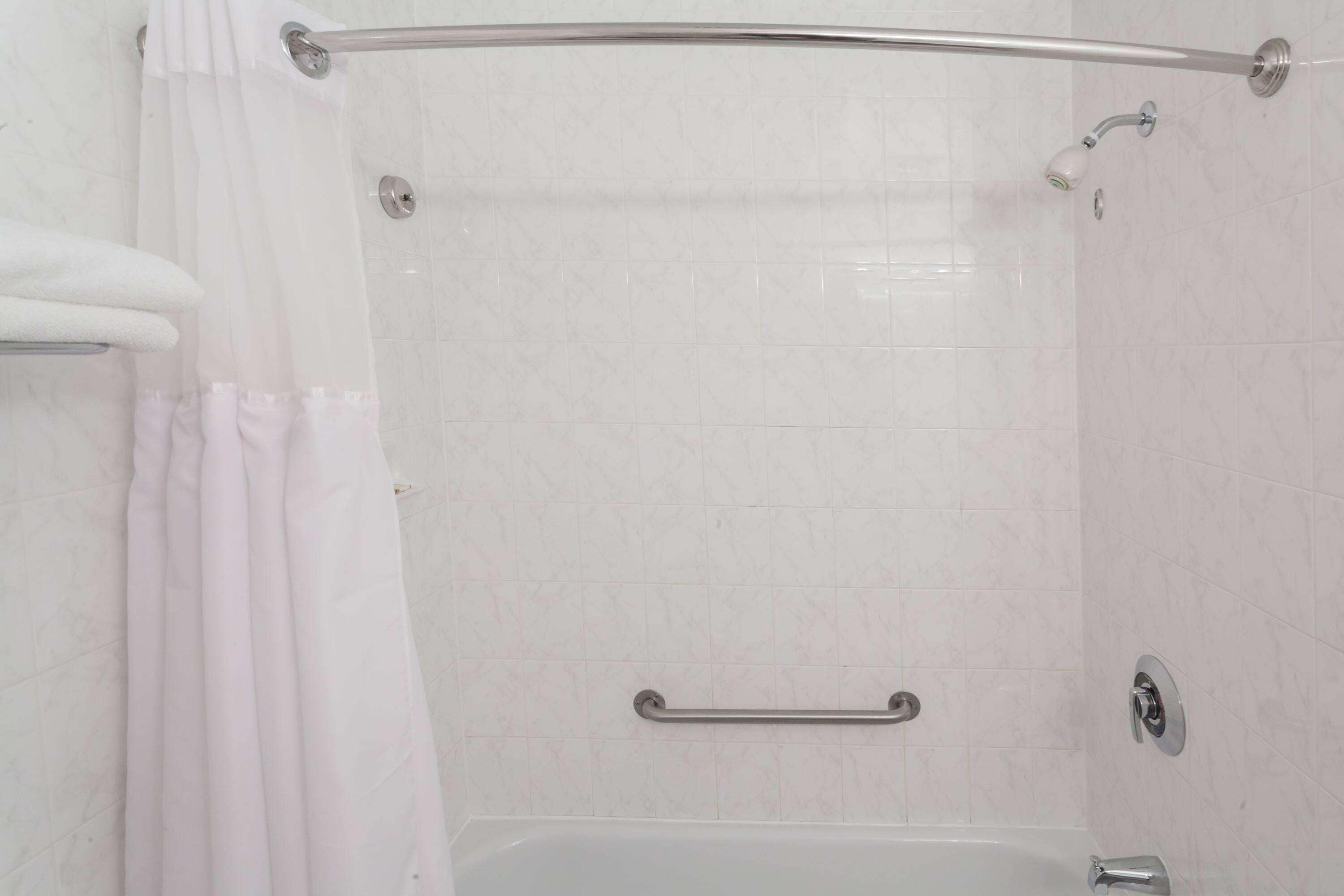 A bathroom with a bathtub, a shower, and a grab bar.