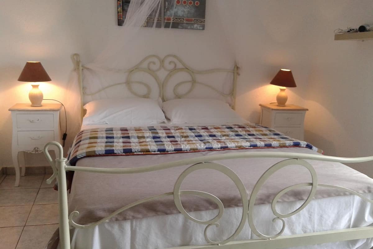A neatly made bed with a checkered bedspread, two bedside tables with lamps, and a wall-mounted artwork above the bed.