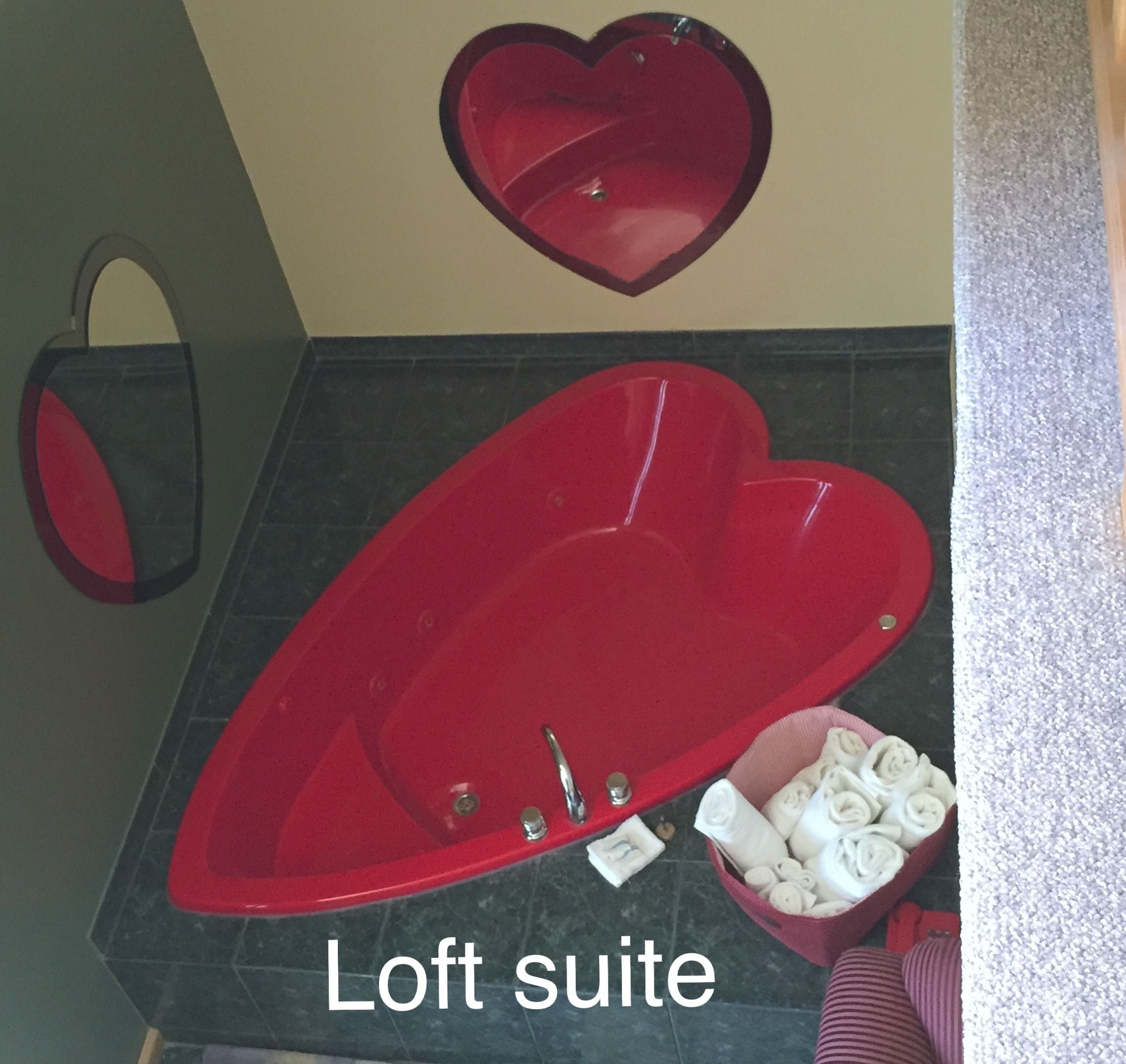 A red bathtub with heart-shaped designs, a heart-shaped towel rack, and a heart-shaped soap dish.