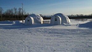 Two igloo-like structures in a snowy landscape. - North Adventure Inn (Cochrane)