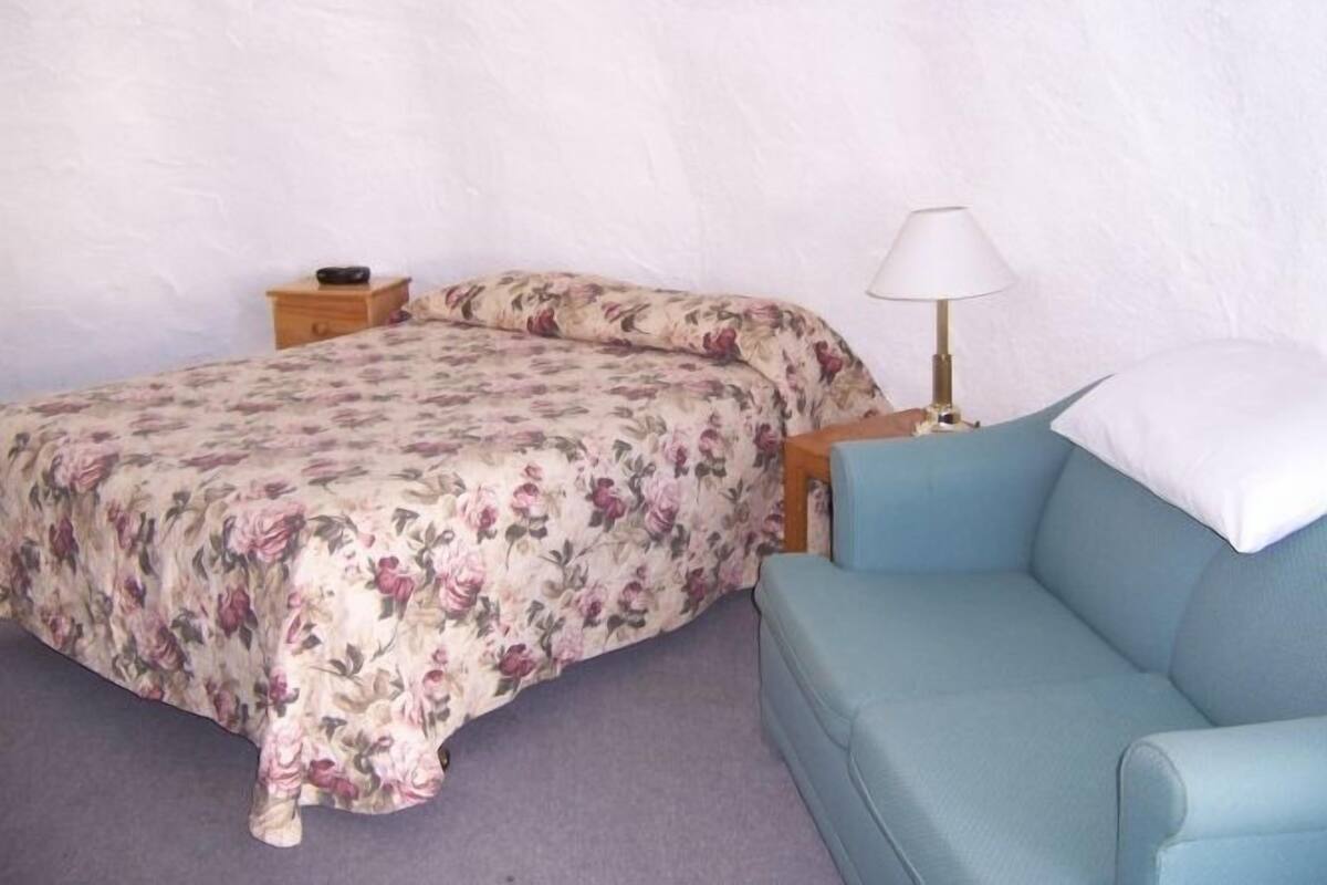 Une chambre à coucher avec un lit, une table de chevet, une lampe et une chaise bleue.
