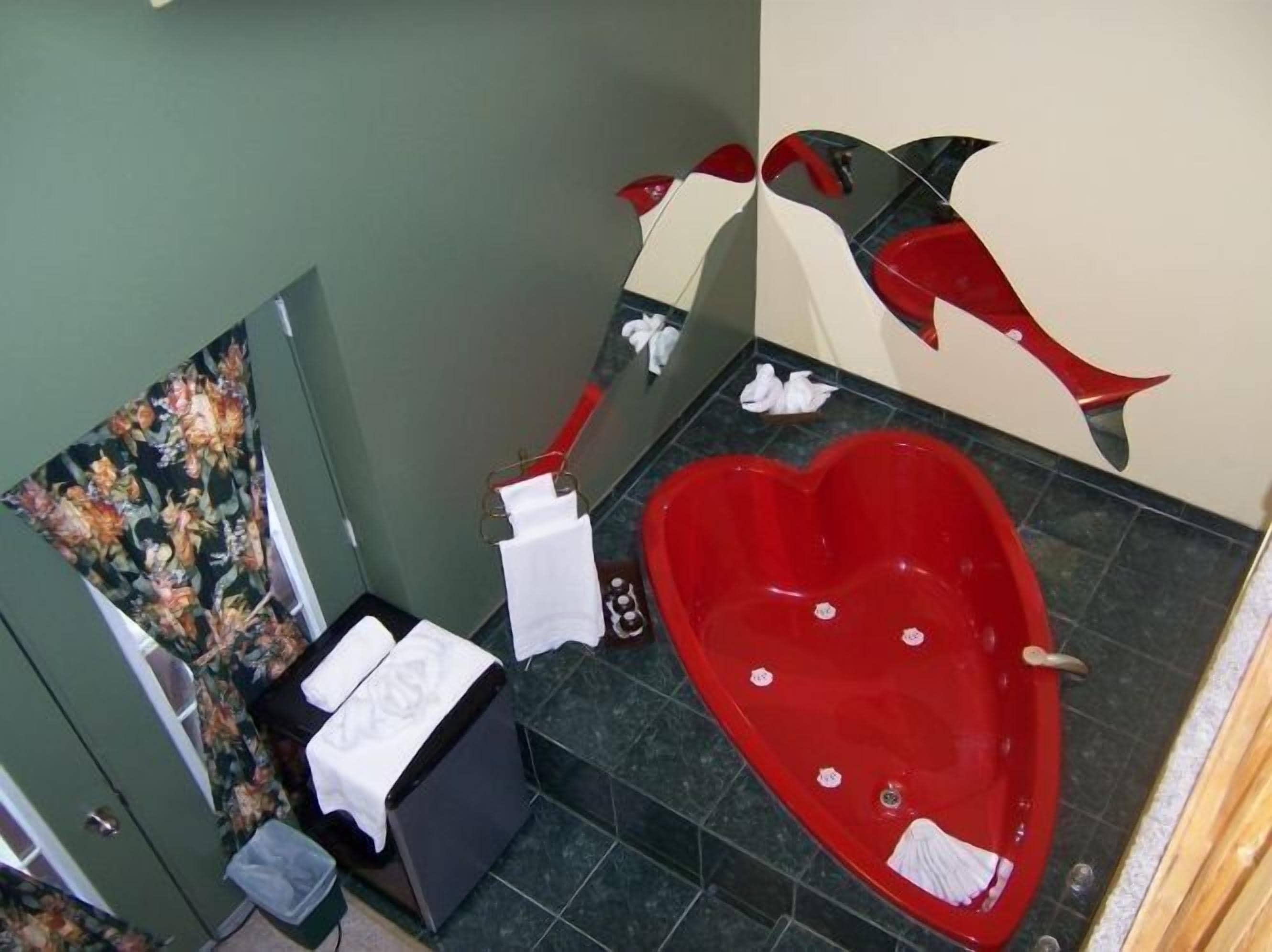 A bathroom with a heart-shaped jacuzzi tub, a shower area, and a decorative mirror.