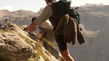 A person hiking on a rocky mountain path with a backpack and a jacket.