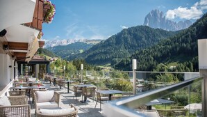 Une terrasse dotée de meubles en osier et offrant une vue sur un paysage montagneux.