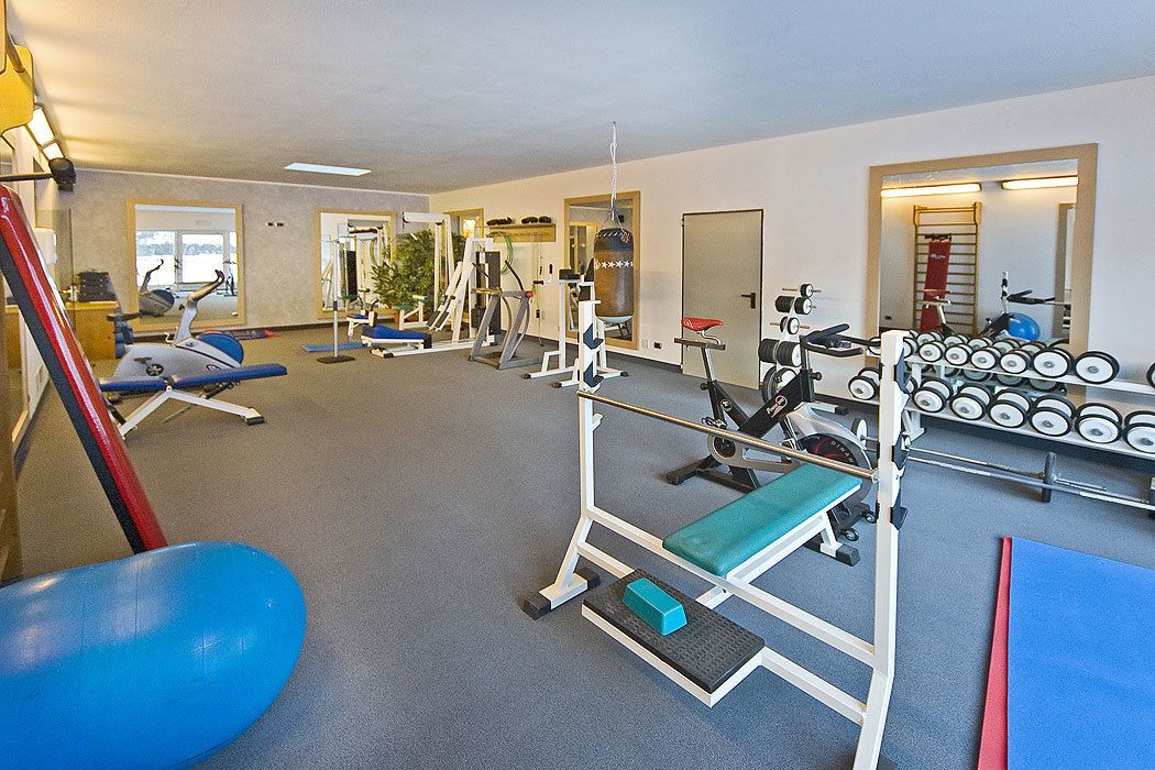 A gym with various exercise equipment, including weight machines, free weights, and cardio machines.