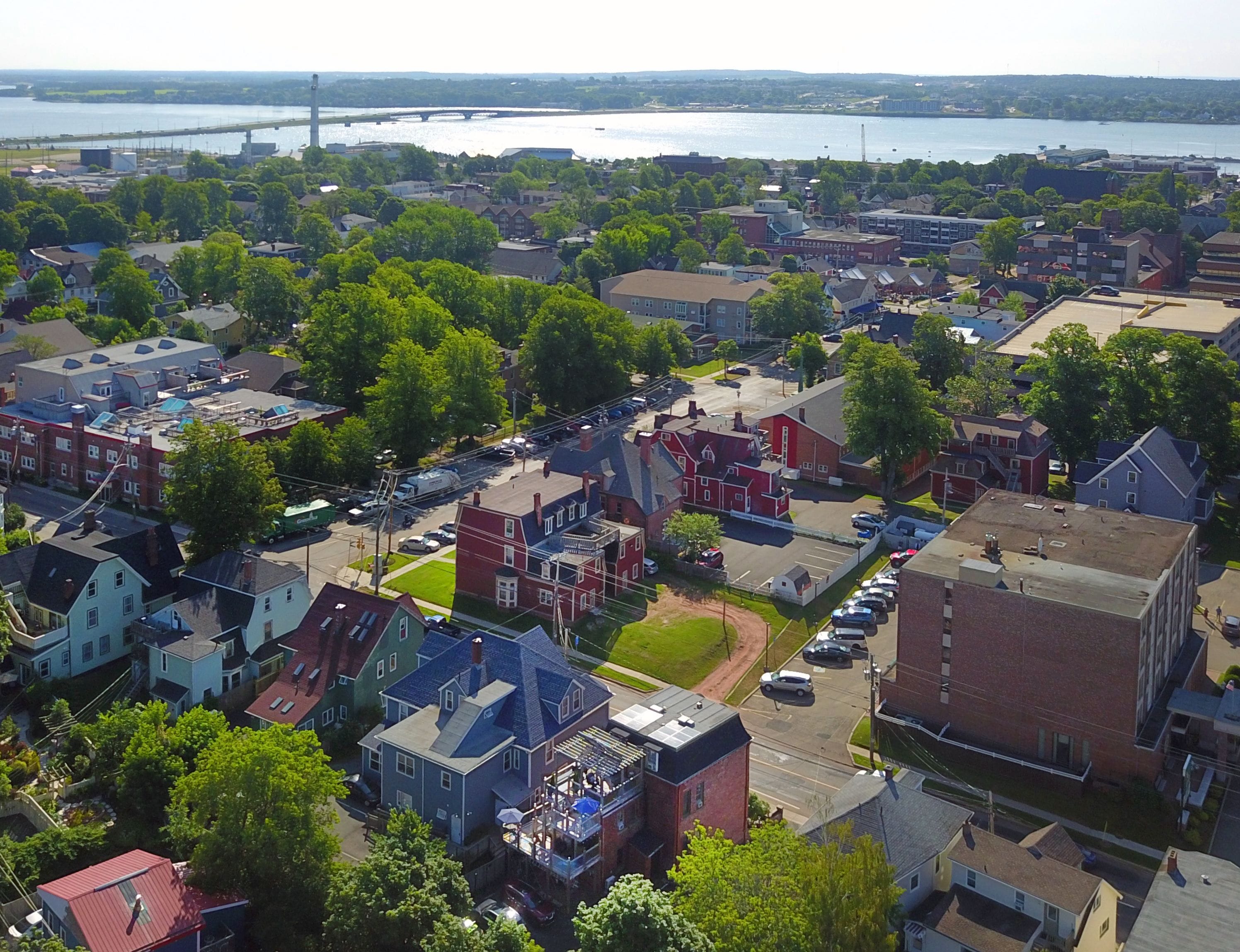 An aerial view of a residential area with houses, streets, and a bridge in the background.