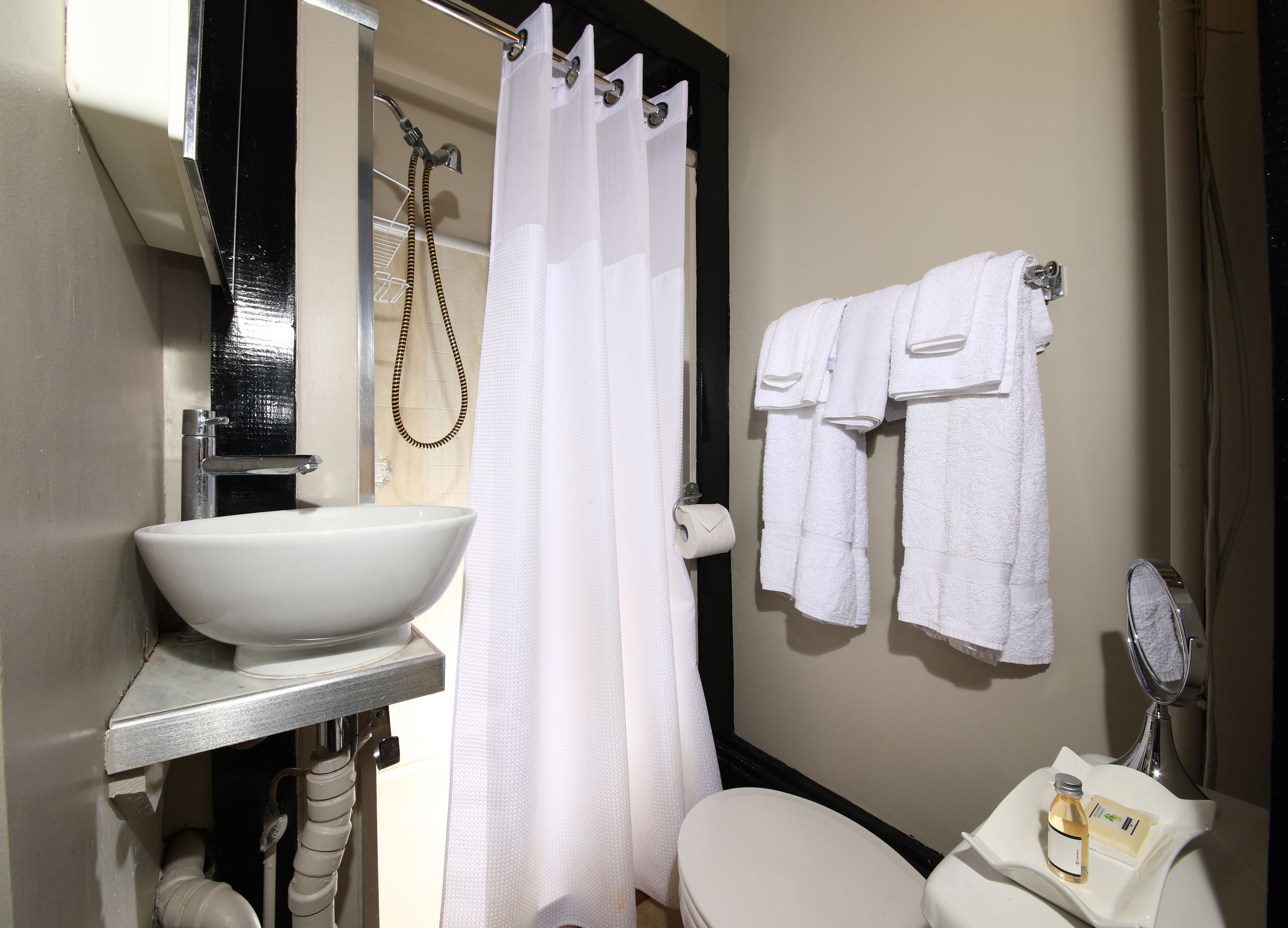 Une salle de bain avec un lavabo blanc, des toilettes et un rideau de douche. Des serviettes sont accrochées au mur.