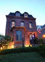 A brick building with a prominent corner entrance, large windows, and a small porch area.