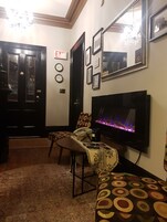 A living room with a fireplace, a television, and a dining area with patterned furniture.