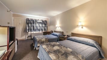Ein Hotelzimmer mit zwei Betten, einem Schreibtisch, einem Stuhl, einem Fernseher und einem Fenster mit Vorhängen.