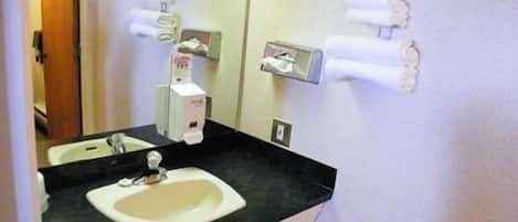 Casa de banho com lavatório, espelho e dispensador de sabonete líquido.