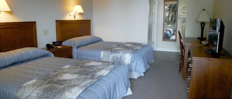Habitación de hotel con dos camas, un escritorio, una silla y un televisor.