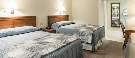 Une chambre d’hôtel avec deux lits, un bureau, une chaise et un miroir.