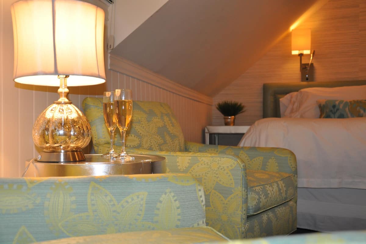 A room with a bed, a nightstand, a lamp, and a decorative glass.
