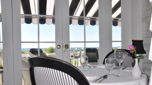 Comedor con una mesa para dos, vista al océano y una puerta que da al exterior.