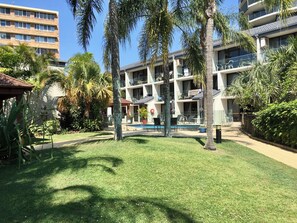 A modern hotel with a pool, outdoor seating, and lush greenery. - Burleigh Palms Holiday Apartments (Burleigh Heads)