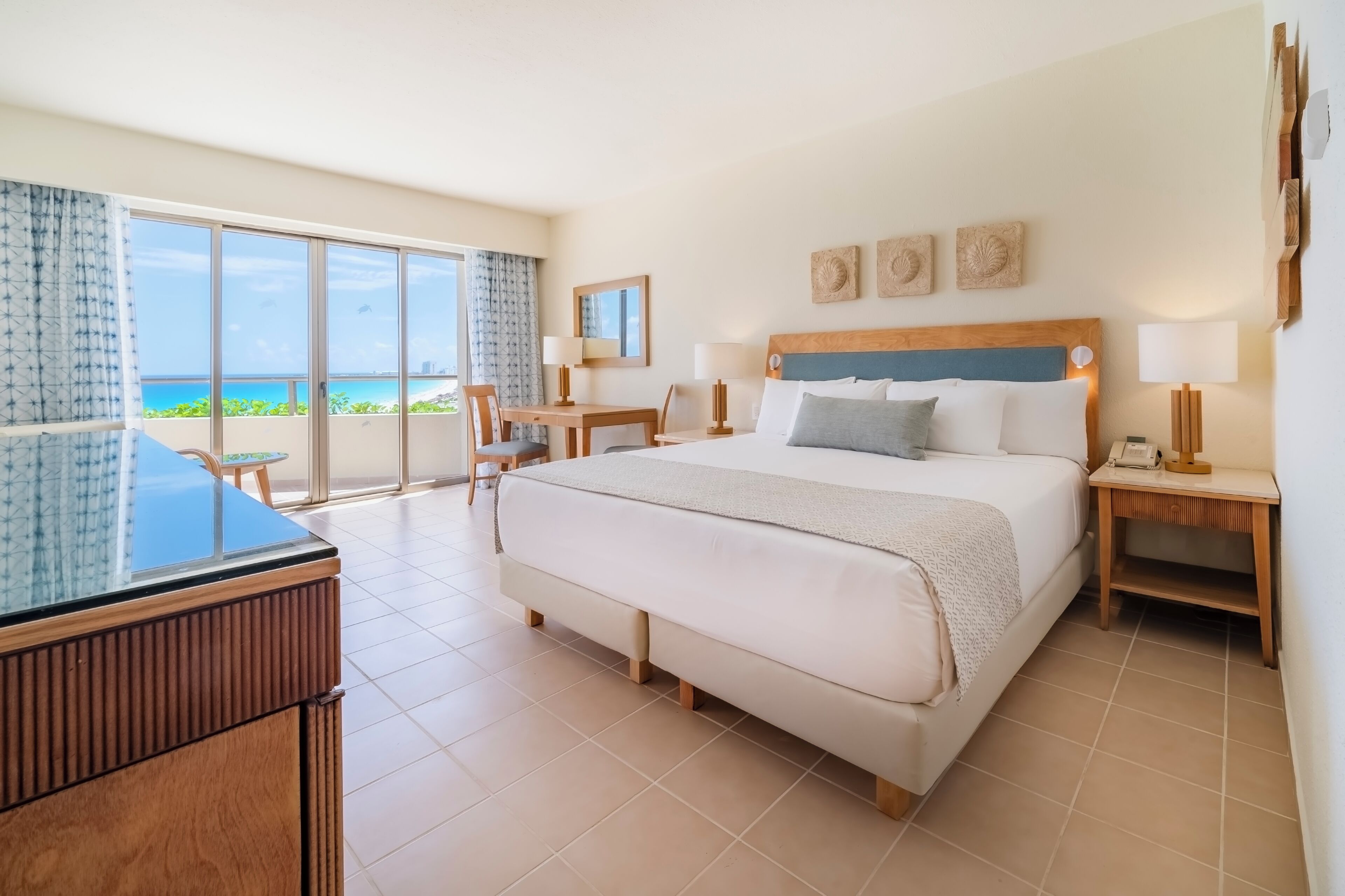 A hotel room with a large bed, a desk, and a view of the ocean.