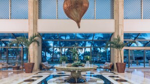 A spacious lobby with a central round table, seating arrangements, and large windows offering views of palm trees. - Iberostar Selection Cancún - All Inclusive (Cancun)