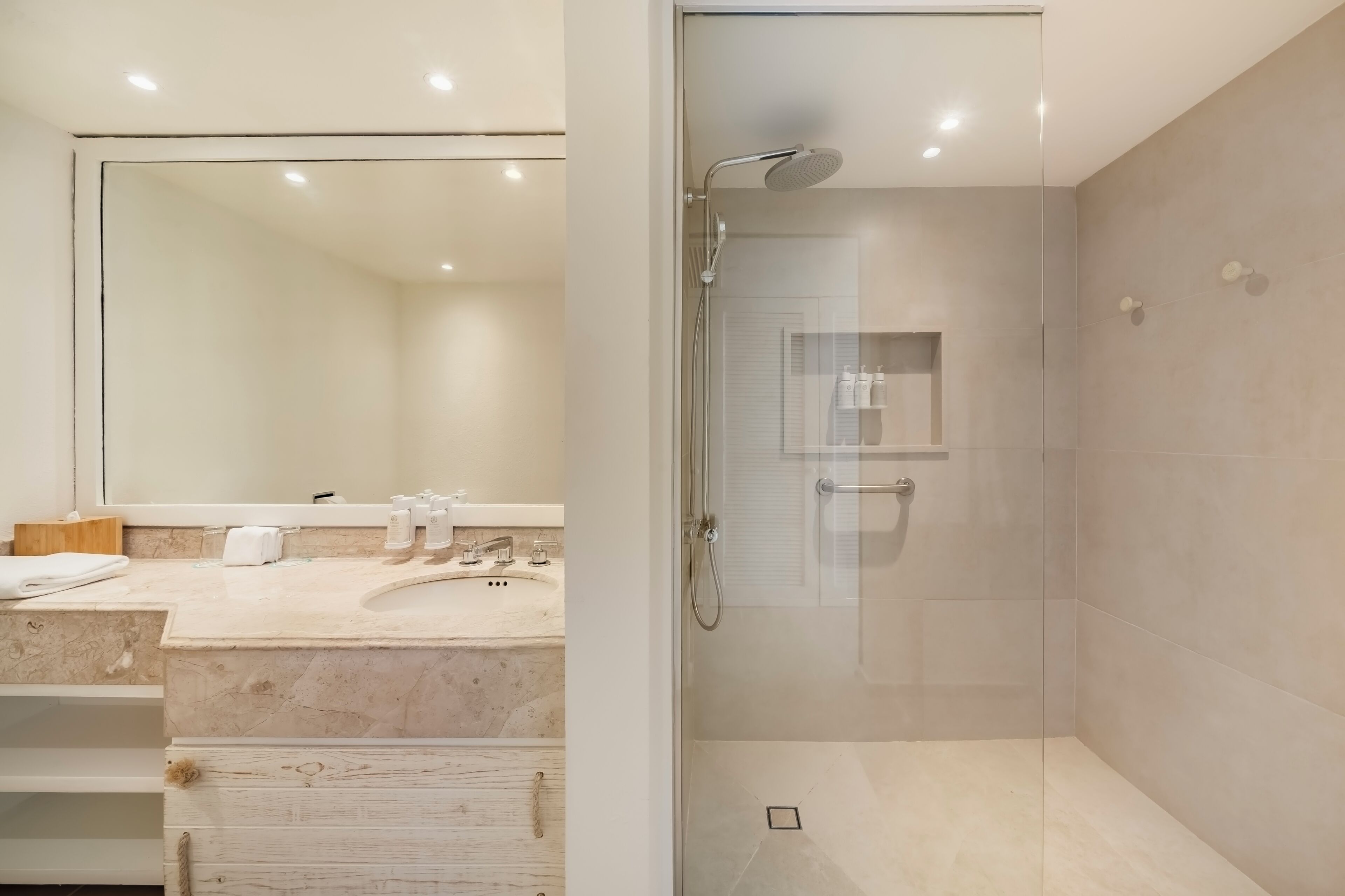 A modern bathroom with a glass-enclosed shower, a large mirror, and a marble countertop.
