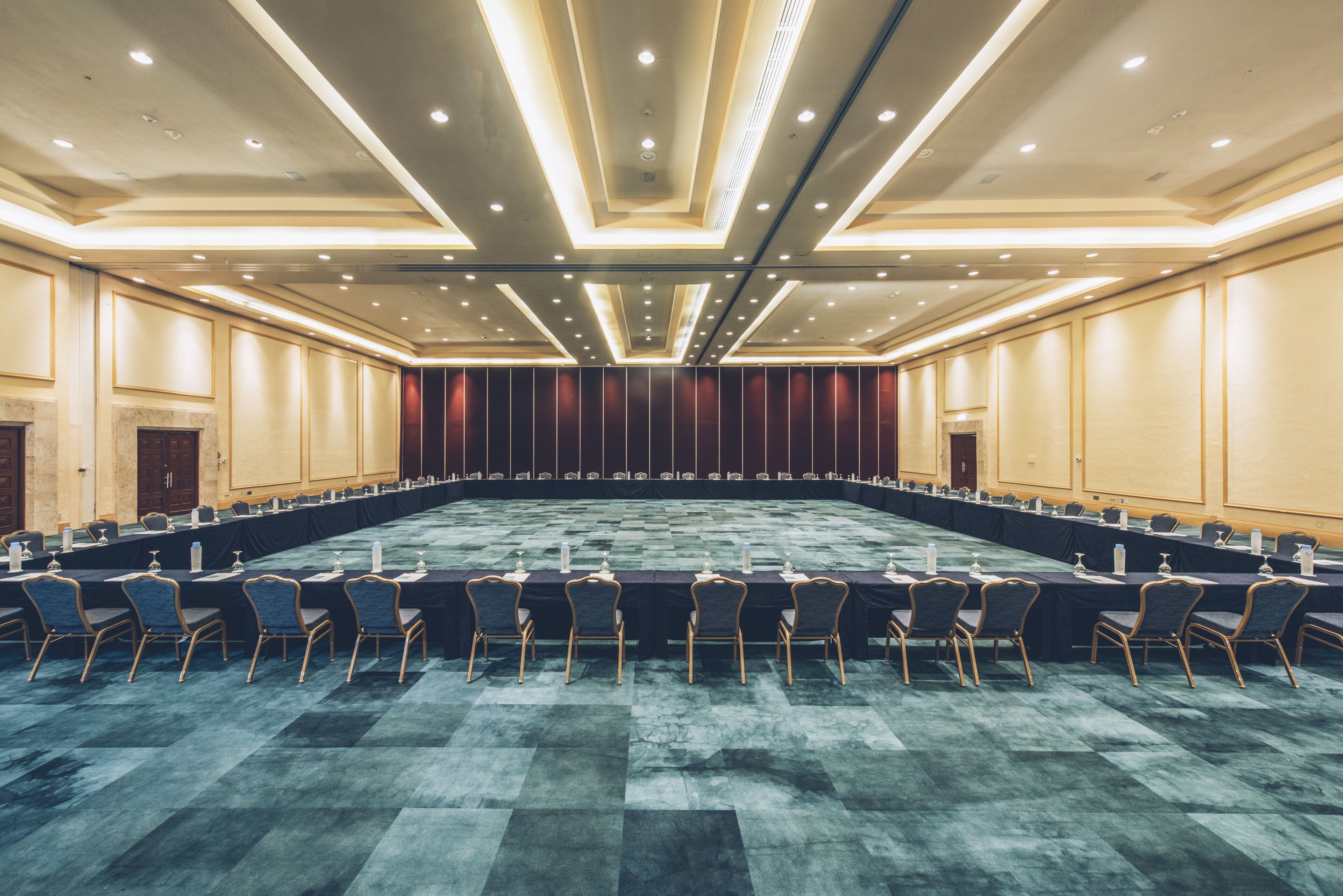 A conference room with a long table, chairs, and a carpeted floor.