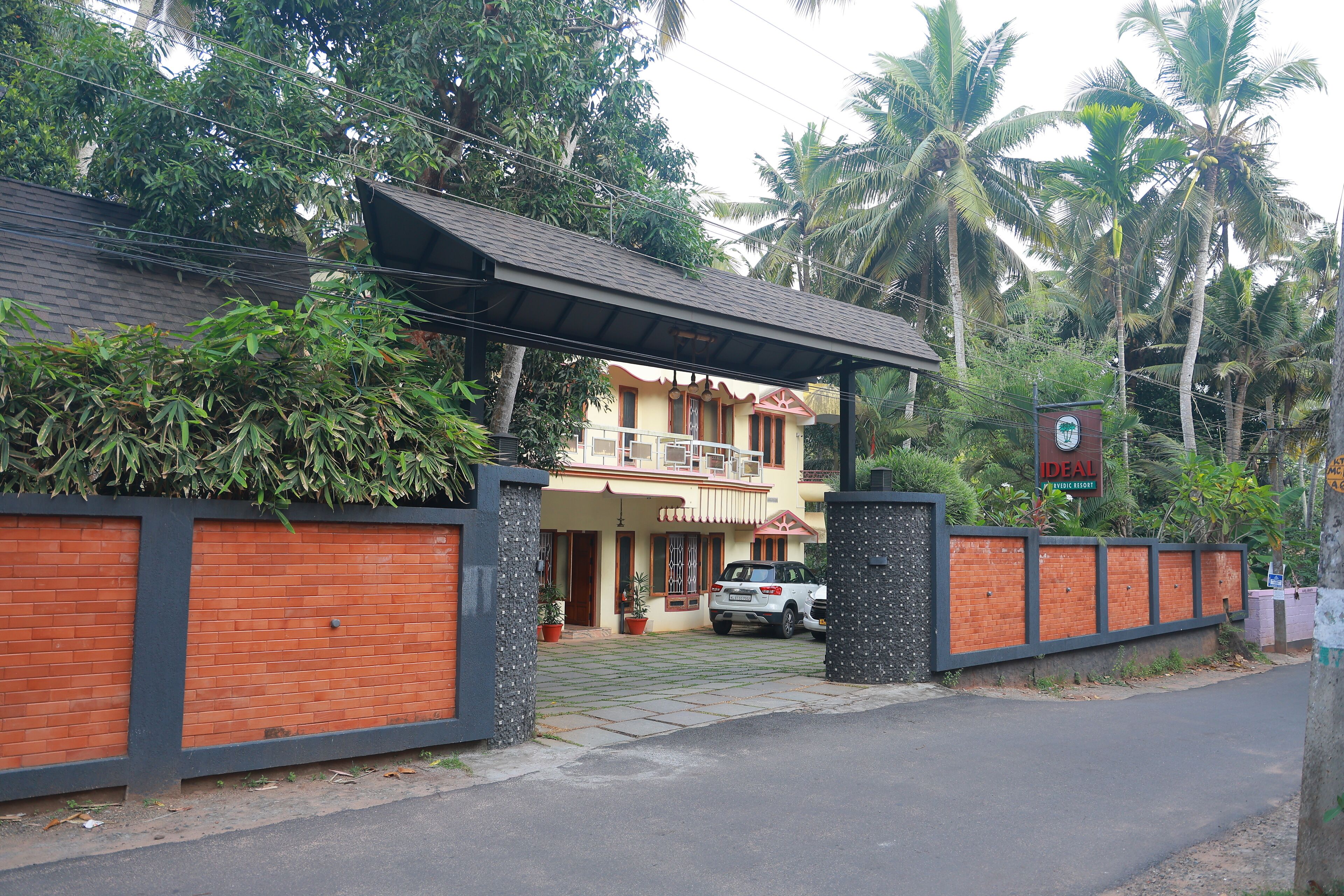 A two-story house with a gated entrance, a covered porch, and a car parked in front.