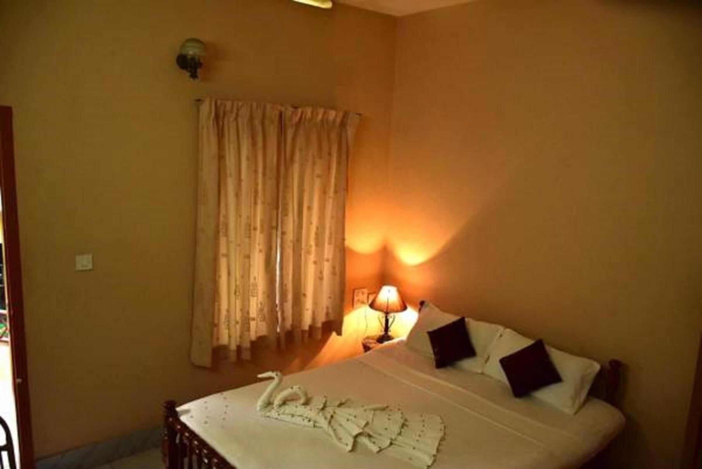 Una habitación de hotel con cama, lámpara y cortina.