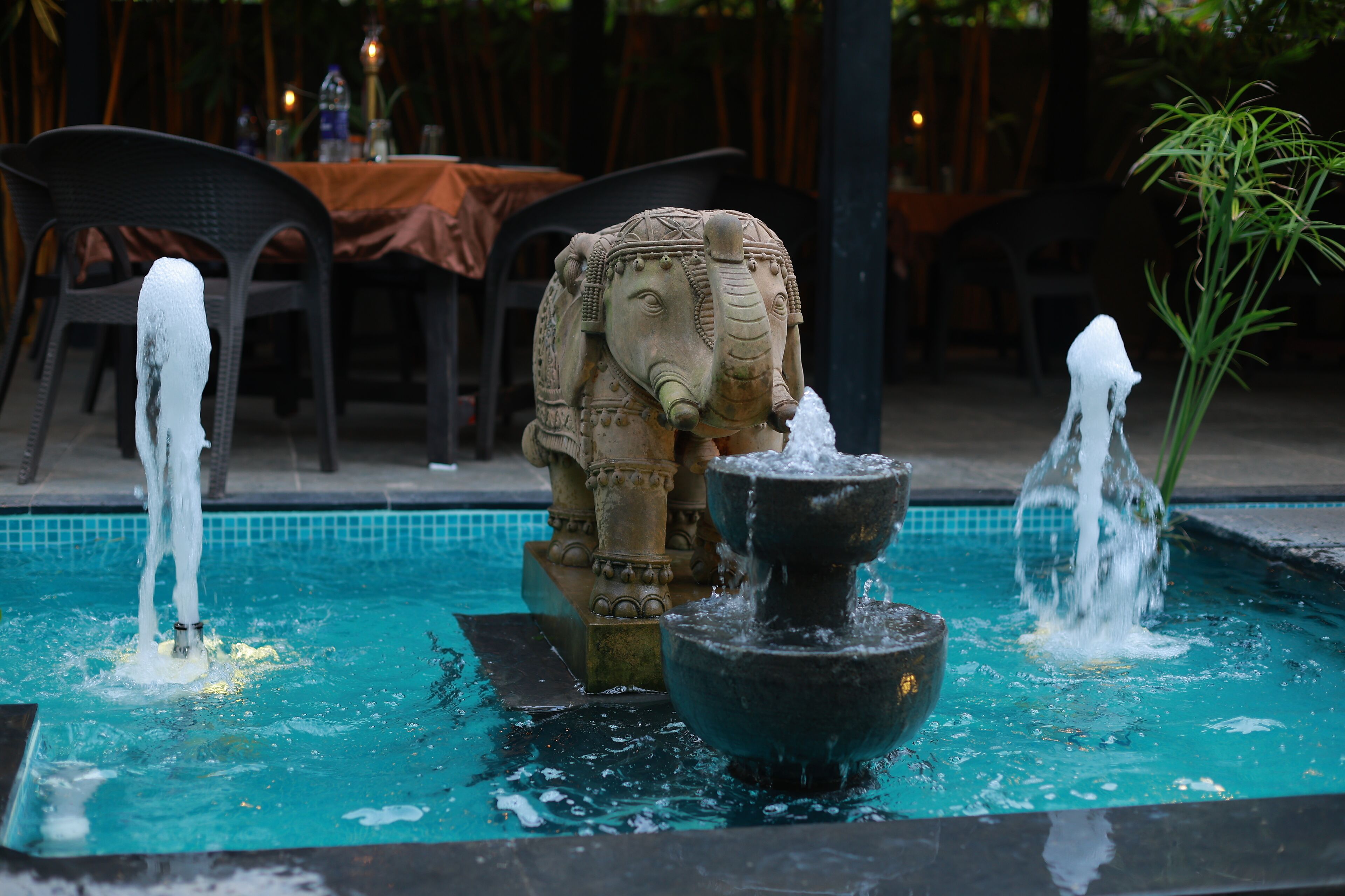 A decorative fountain with an elephant statue in the center, surrounded by a pool.