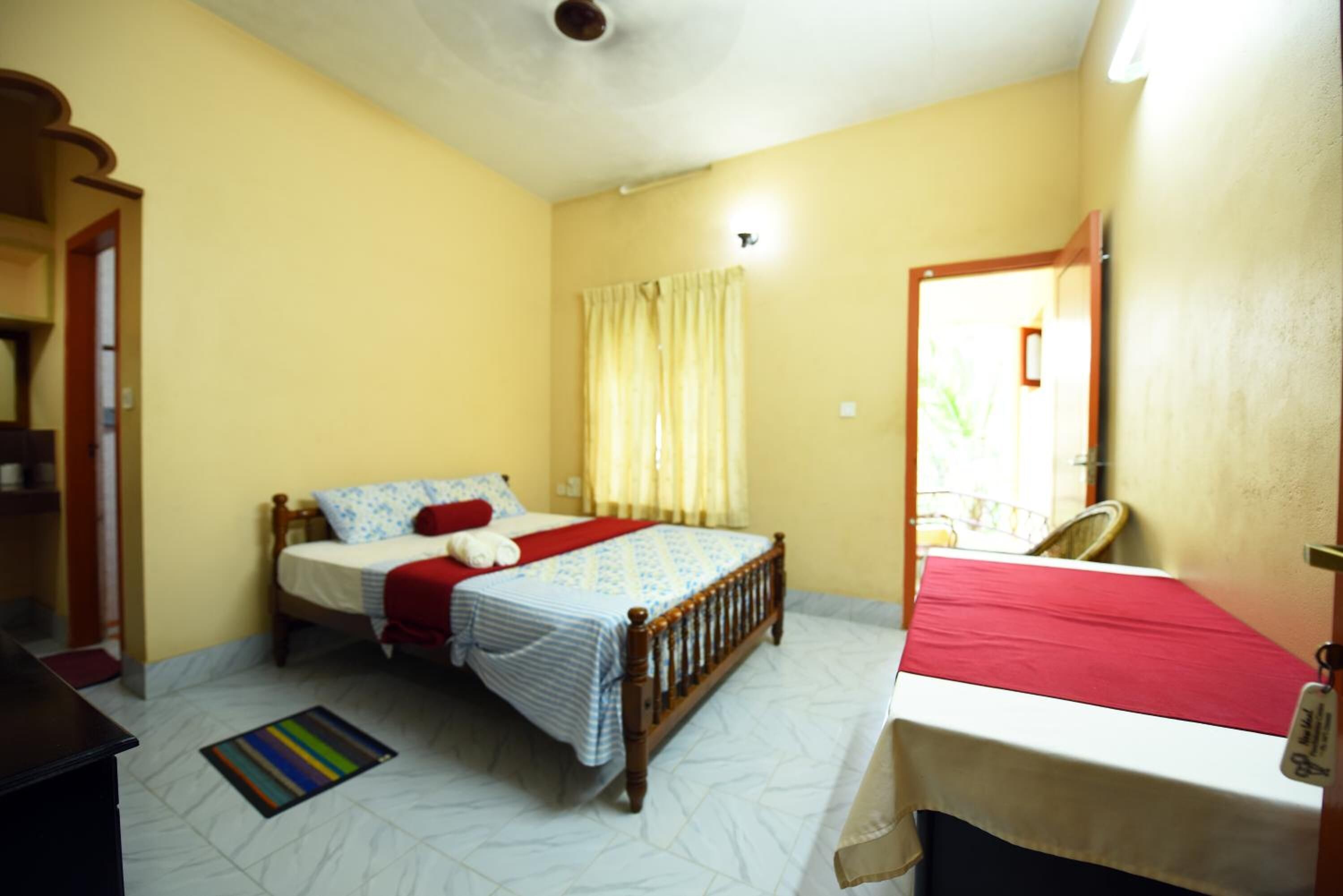 A bedroom with a bed, a bedside table, a chair, and a window with curtains.